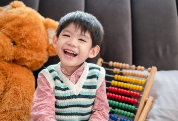 asian boy smiling and laughing happily lying on bed